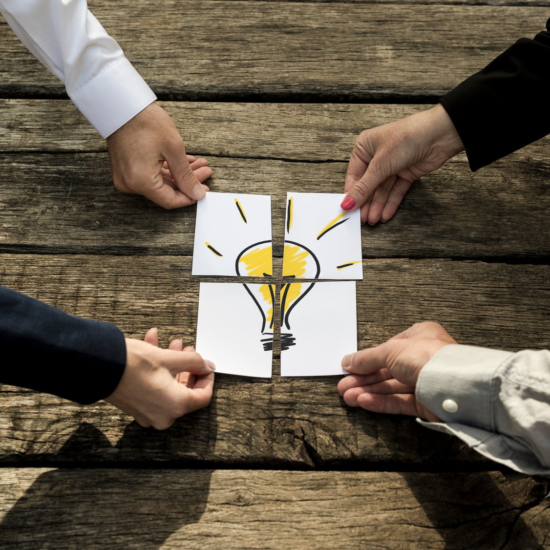 Four Business People Putting Together a Light Bulb